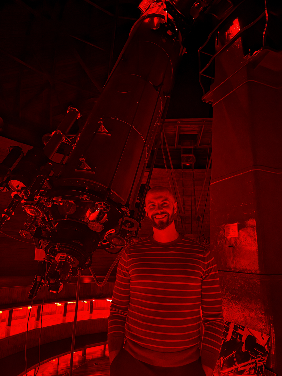 Dagomar Degroot standing beside Percival Lowell’s refracting telescope at Lowell Observatory